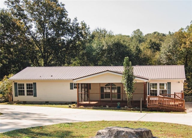 single story home with crawl space, a deck, metal roof, a front lawn, and driveway