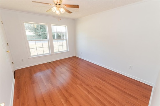 empty room featuring ceiling fan, ornamental molding, baseboards, and light wood-type flooring
