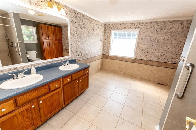 full bathroom with wallpapered walls, toilet, a wainscoted wall, and a sink