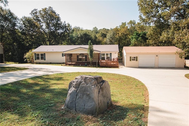 ranch-style home with concrete driveway, a front yard, an outdoor structure, and metal roof
