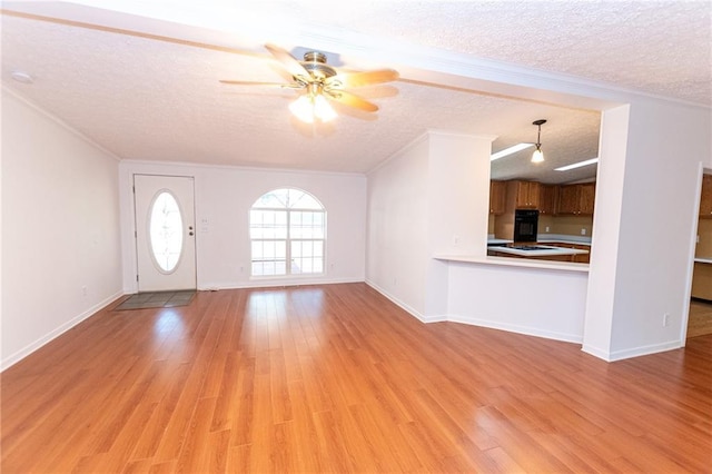 unfurnished living room with a textured ceiling, ornamental molding, ceiling fan, light wood-style flooring, and baseboards