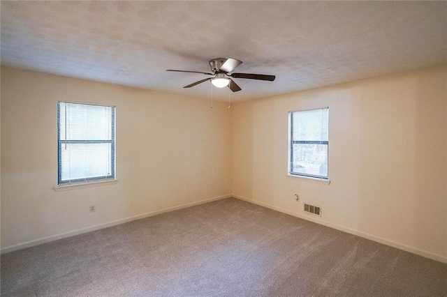 carpeted spare room featuring ceiling fan and a healthy amount of sunlight