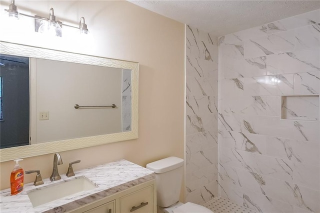 bathroom featuring tiled shower, vanity, and toilet