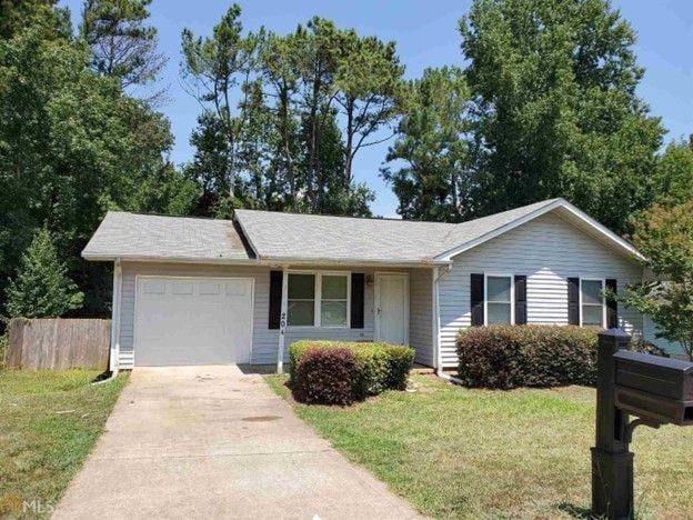 ranch-style house featuring a front lawn, concrete driveway, fence, and an attached garage