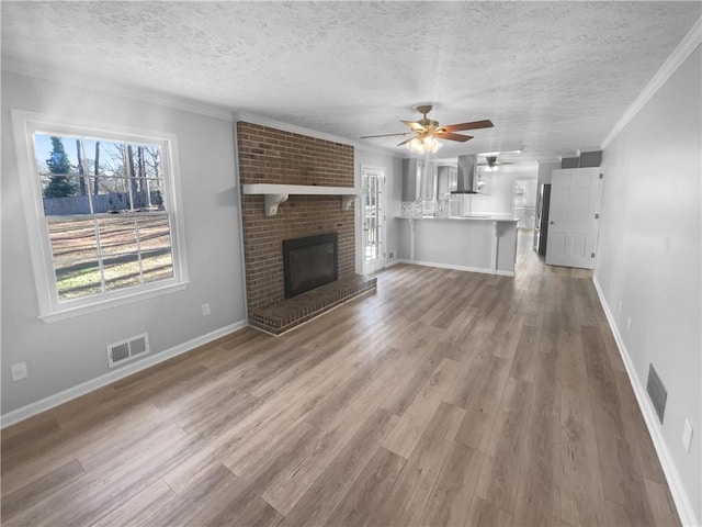 unfurnished living room with crown molding, a fireplace, a textured ceiling, and hardwood / wood-style flooring