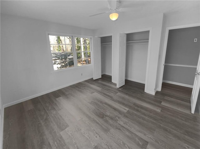 unfurnished bedroom featuring ceiling fan, dark hardwood / wood-style flooring, and two closets