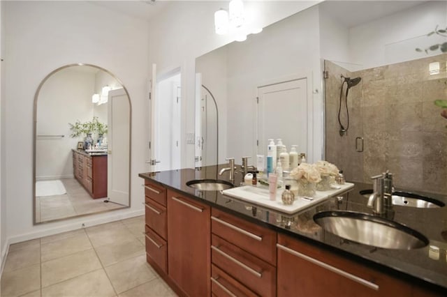 bathroom featuring double vanity, a sink, a tile shower, and tile patterned floors