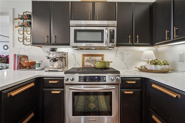 kitchen with dark cabinets, decorative backsplash, stainless steel appliances, and light countertops