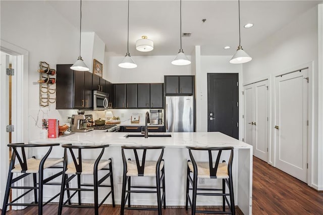 kitchen featuring dark wood finished floors, a breakfast bar area, a peninsula, stainless steel appliances, and a sink