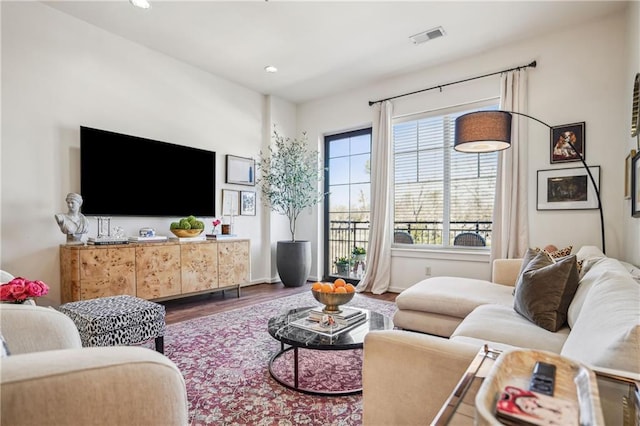 living room with recessed lighting, visible vents, and wood finished floors