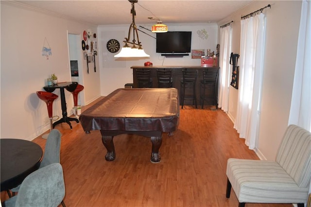 game room with bar, pool table, ornamental molding, and light wood-type flooring