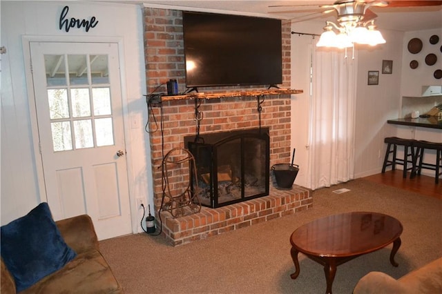 carpeted living room with a fireplace and ceiling fan