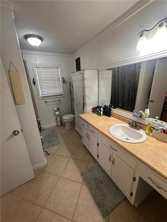 bathroom with tile patterned floors, toilet, crown molding, a textured ceiling, and vanity