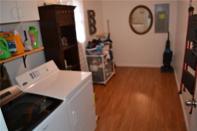 washroom featuring cabinets, electric panel, washer and dryer, and light wood-type flooring