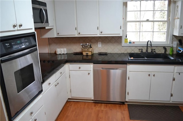 kitchen featuring white cabinetry, sink, backsplash, and stainless steel appliances