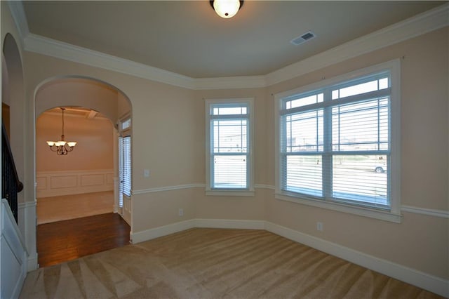 carpeted empty room featuring crown molding and a chandelier