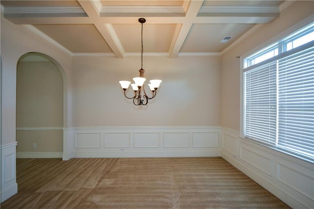 carpeted empty room with a notable chandelier, beam ceiling, and ornamental molding