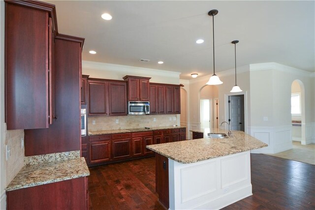 kitchen featuring sink, hanging light fixtures, dark wood-type flooring, a kitchen island with sink, and appliances with stainless steel finishes