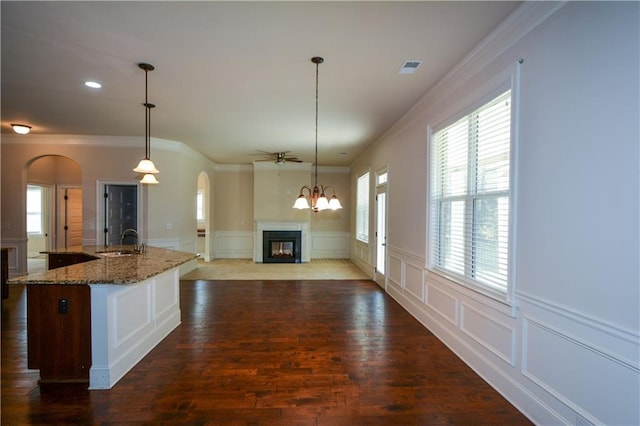 kitchen featuring dark stone counters, crown molding, dark wood-type flooring, sink, and pendant lighting