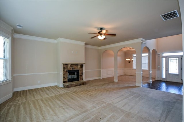 unfurnished living room featuring a stone fireplace, crown molding, and plenty of natural light