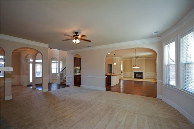 unfurnished living room with crown molding, ceiling fan, and a healthy amount of sunlight