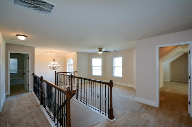 hall with ornamental molding, light colored carpet, and a notable chandelier