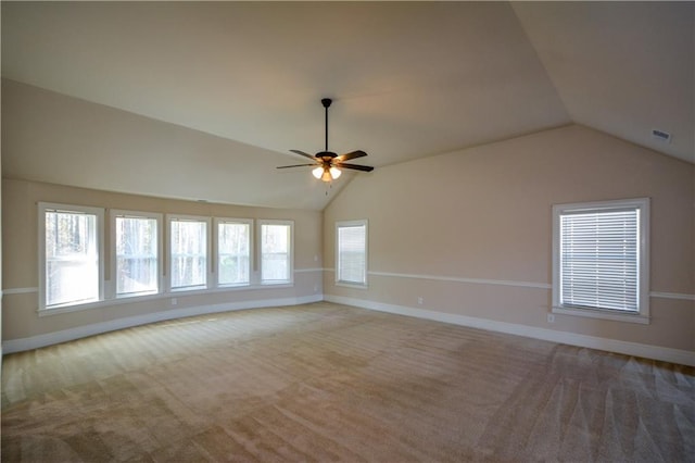 carpeted empty room featuring plenty of natural light, ceiling fan, and lofted ceiling