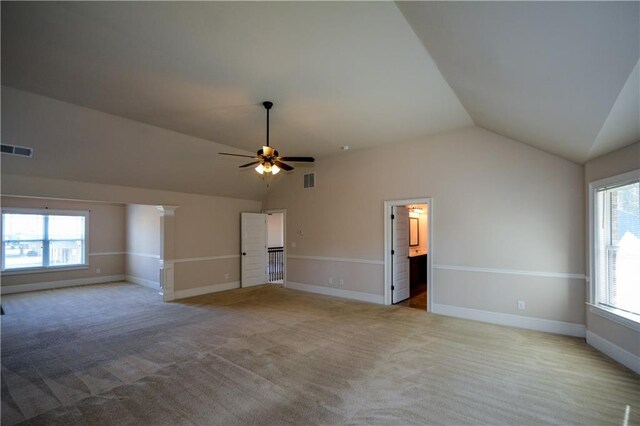 interior space with ensuite bathroom, ceiling fan, light colored carpet, and vaulted ceiling