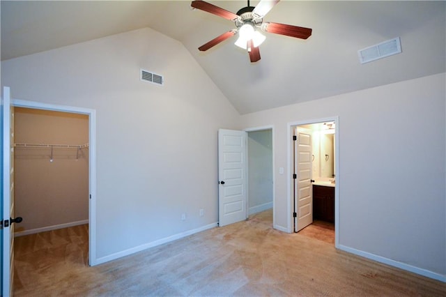 unfurnished bedroom with connected bathroom, a spacious closet, ceiling fan, and light carpet