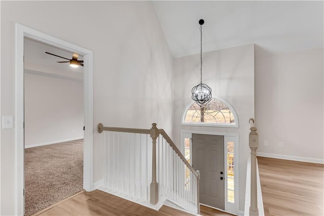 foyer featuring high vaulted ceiling, a notable chandelier, baseboards, and wood finished floors