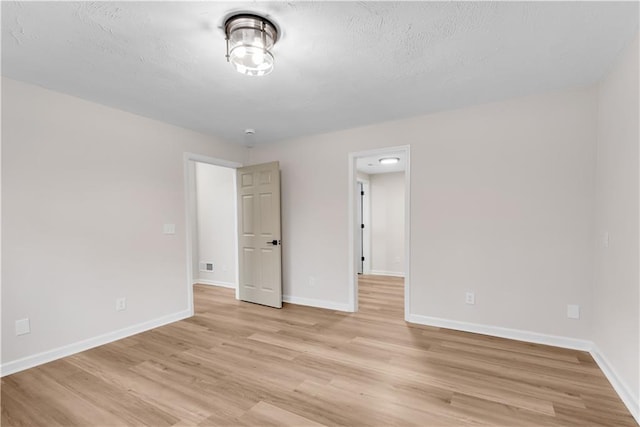 unfurnished room featuring light wood-type flooring, visible vents, and baseboards