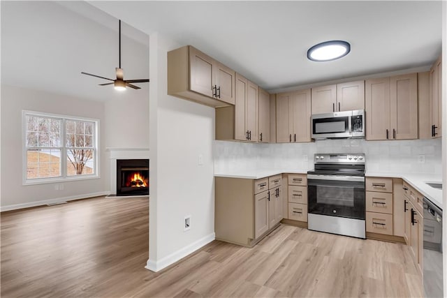 kitchen featuring open floor plan, light countertops, appliances with stainless steel finishes, and backsplash