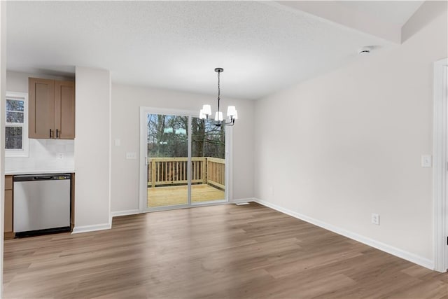 unfurnished dining area featuring light wood-type flooring, baseboards, and a notable chandelier