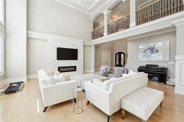 3423 Jamont Blvd, Alpharetta, GA 30022 - living area featuring a glass covered fireplace, a towering ceiling, wood finished floors, arched walkways, and crown molding