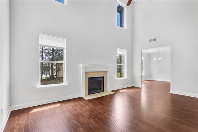 1433 Sand Way, Lawrenceville, GA 30045 - unfurnished living room with healthy amount of natural light, a towering ceiling, a fireplace with flush hearth, dark wood finished floors, and a chandelier