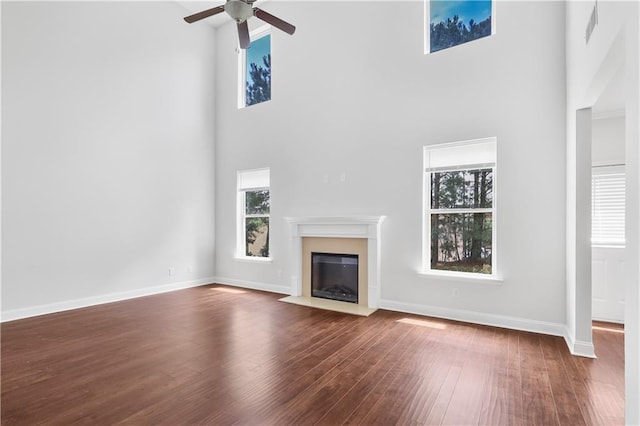 1433 Sand Way, Lawrenceville, GA 30045 - unfurnished living room with a towering ceiling, dark wood finished floors, ceiling fan, a fireplace with flush hearth, and baseboards