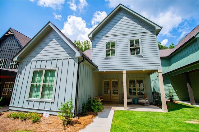 rear view of house featuring board and batten siding, a patio area, and a lawn