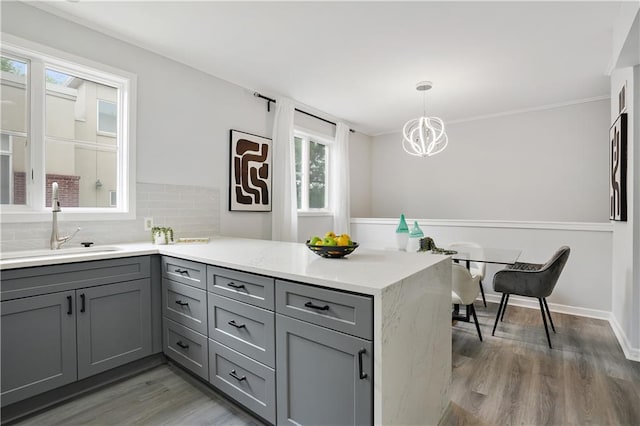 kitchen featuring hanging light fixtures, dark hardwood / wood-style floors, gray cabinetry, and kitchen peninsula