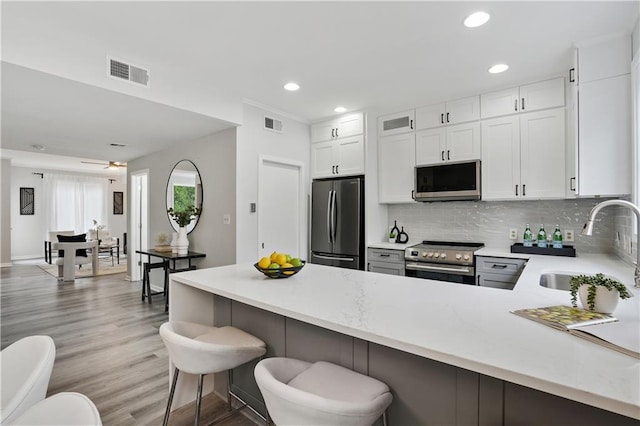 kitchen featuring sink, white cabinets, a kitchen breakfast bar, kitchen peninsula, and stainless steel appliances