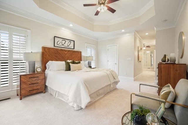 bedroom featuring baseboards, visible vents, light colored carpet, a tray ceiling, and crown molding