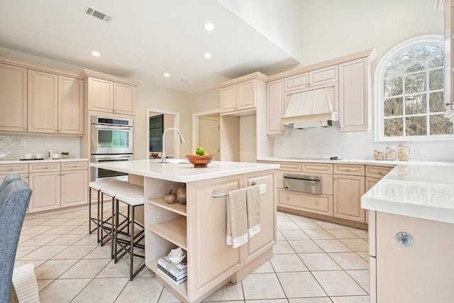 kitchen featuring premium range hood, visible vents, stainless steel double oven, and light tile patterned flooring