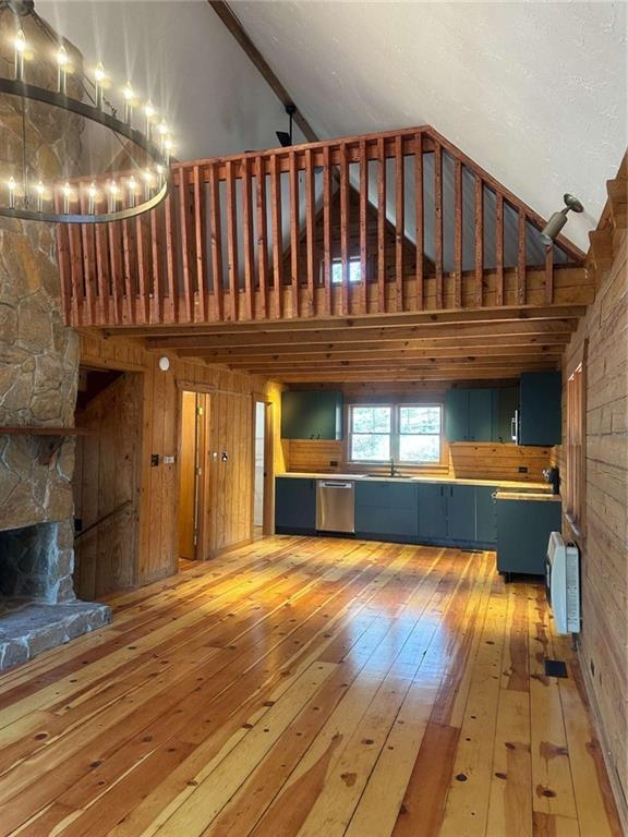 68 Star Lake Ln, Sautee Nacoochee, GA 30571 - unfurnished living room with high vaulted ceiling, light wood-style flooring, a sink, wood walls, and a chandelier