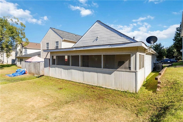 exterior space featuring central air condition unit, a lawn, and a sunroom