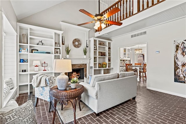 living room featuring high vaulted ceiling, a premium fireplace, visible vents, and baseboards