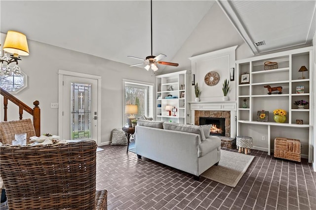 living area featuring brick floor, a fireplace, baseboards, and a ceiling fan