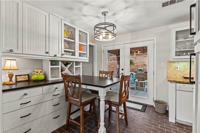 dining area featuring french doors, brick floor, visible vents, and an inviting chandelier