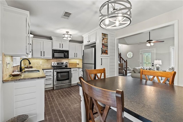 kitchen with appliances with stainless steel finishes, visible vents, a sink, and tasteful backsplash