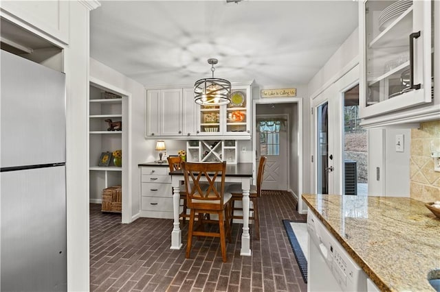 dining room with brick floor, baseboards, and a chandelier