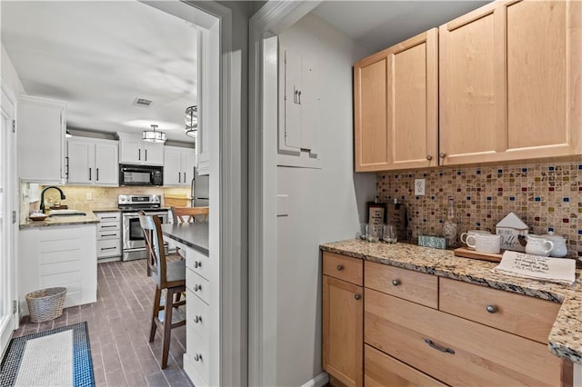 kitchen with black microwave, decorative backsplash, electric stove, and light brown cabinetry