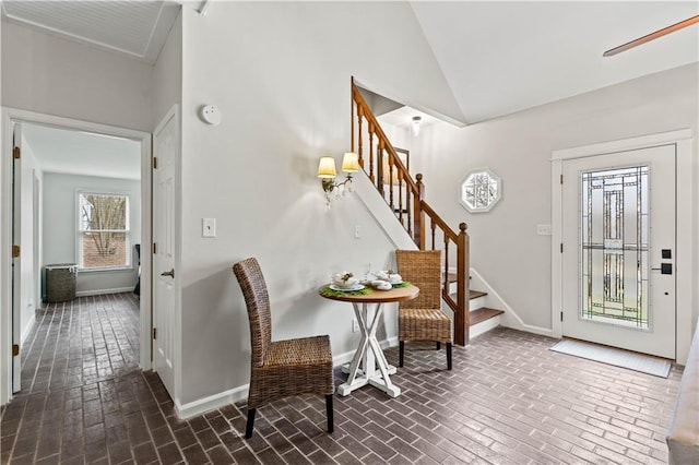 foyer entrance with brick floor, stairs, and baseboards